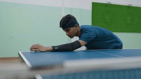 Young tennis player in blue shirt and headband prepares serve by lifting ball into air while holding racket, focused on technique and precision during indoor training session on green and white court - Powered by Shutterstock - Get 15% off with code: PIKWIZARD15