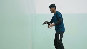 Side view of tennis player practicing against wall indoors, holding racket with focus, striking ball with controlled movement, wearing sportswear and headband - Powered by Shutterstock - Get 15% off with code: PIKWIZARD15