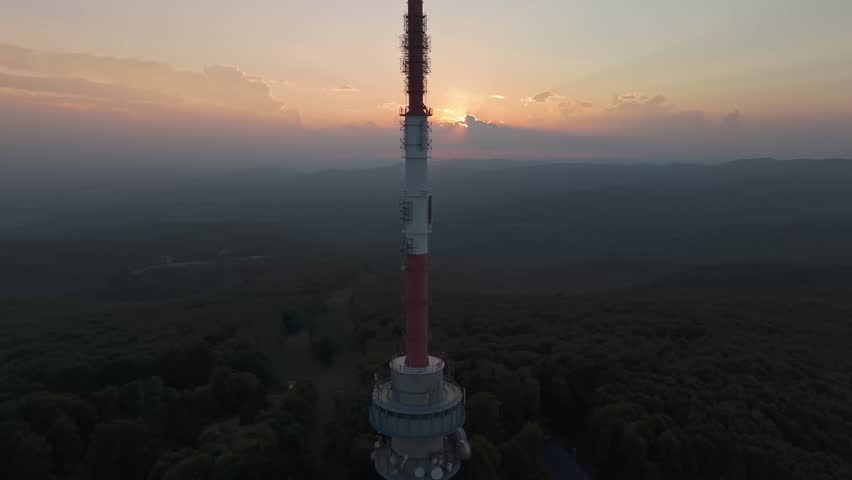 Dramatic aerial view as the sun sets behind the top part of the Kékes TV Tower with the mysterious Mátra Mountains in the background in Hungary.