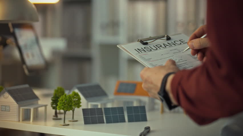An insurance agent fills out essential documents for a private home featuring solar panels. This detailed work takes place in a contemporary office during daylight hours