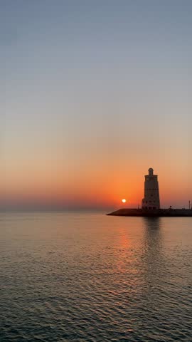 Sunset at sea. View of an old lighthouse at sunset.