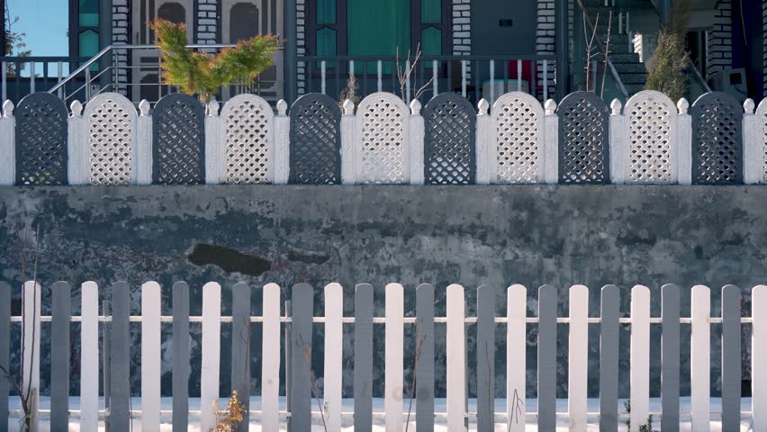 White picket fence surrounded by greenery in Bhaderwah, Jammu and Kashmir, India.