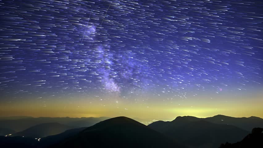 Stars trails over mountains at night, Timelapse of stars and galaxy over mountain silhouette at night