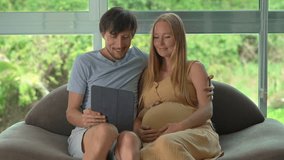 Happy pregnant couple sitting on a couch, smiling while reading good news on a tablet the husband holds, enjoying a joyful and emotional moment together during pregnancy. Slowmotion video. - Powered by Shutterstock - Get 15% off with code: PIKWIZARD15