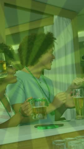 Animation of green lines over happy diverse friends wearing clover shape items and drinking beer. social media and st patrick