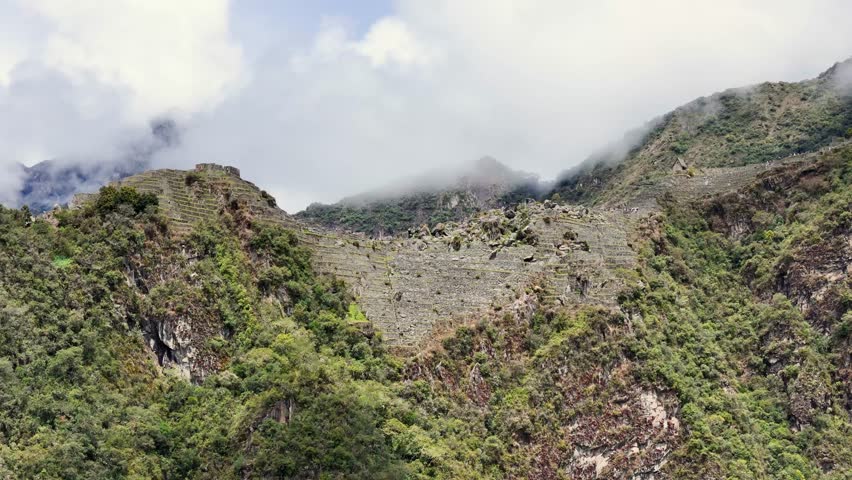 dynamic shot moves directly in from mountainside towards the lower section of Machu Picchu