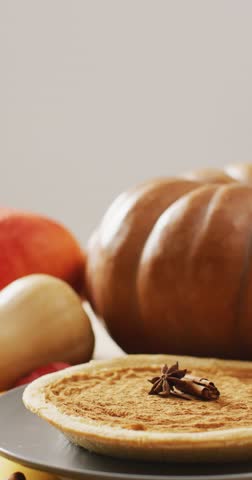 Vertical video of pumpkin pie with spices and pumpkins. Halloween, autumn, tradition and celebration concept.