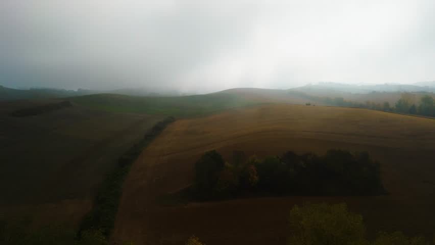 Foreboding Fog Drift Over Layered Hills and Farmland Under Distant Sunlight