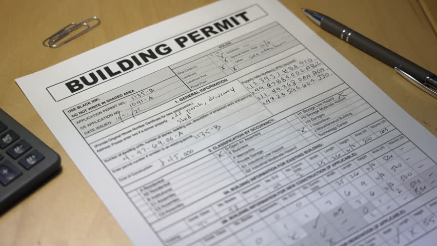 Close-up of an approved building permit stamped in red ink on a desk with a pen and calculator, symbolizing project approval and construction success. Fictional data. 14917  	