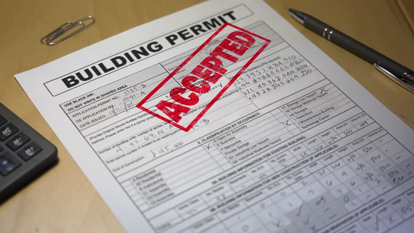 Close-up of an approved building permit stamped in red ink on a desk with a pen and calculator, symbolizing project approval and construction success. Fictional data. 14917  	