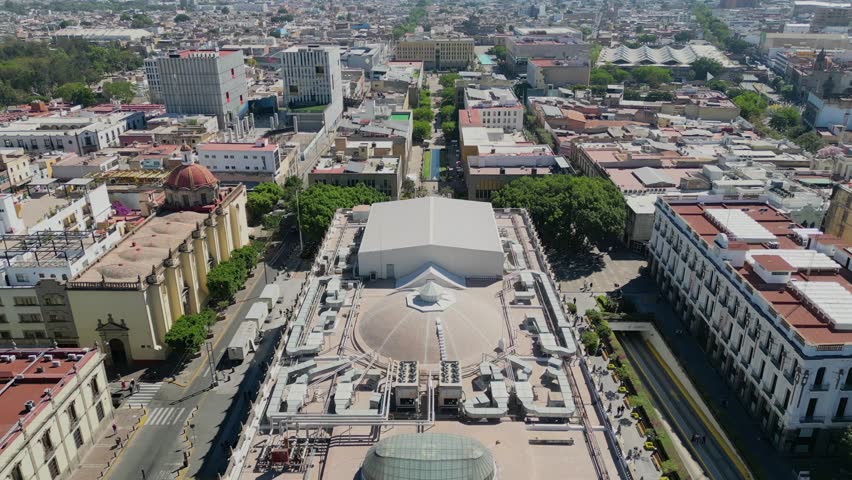 Aerial footage retreating from Teatro Degollado showing main plaza, surrounding buildings and city skyline in Guadalajara, Mexico