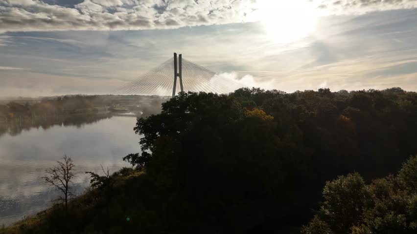 Aerial view of Redzin Bridge (Most Rędziński) in Wroclaw, Poland, surrounded by morning fog and forest under dramatic sunrise sky – scenic drone landscape of autumn mist and architecture