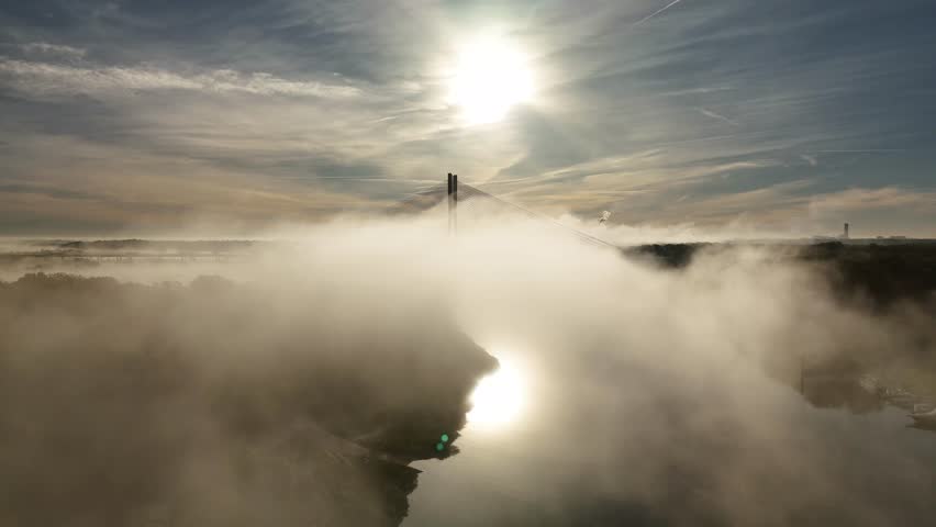 Aerial view of Redzin Bridge (Most Rędziński) in Wroclaw, Poland, surrounded by morning fog and forest under dramatic sunrise sky – scenic drone landscape of autumn mist and architecture