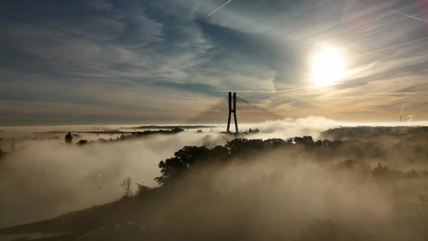 Aerial view of Redzin Bridge (Most Rędziński) in Wroclaw, Poland, surrounded by morning fog and forest under dramatic sunrise sky – scenic drone landscape of autumn mist and architecture