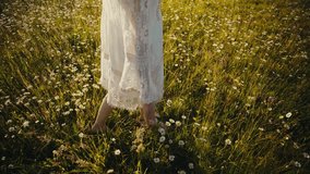 Barefoot woman in flowing white dress walking gracefully through a sunny meadow filled with blooming daisy wildflowers. - Powered by Shutterstock - Get 15% off with code: PIKWIZARD15