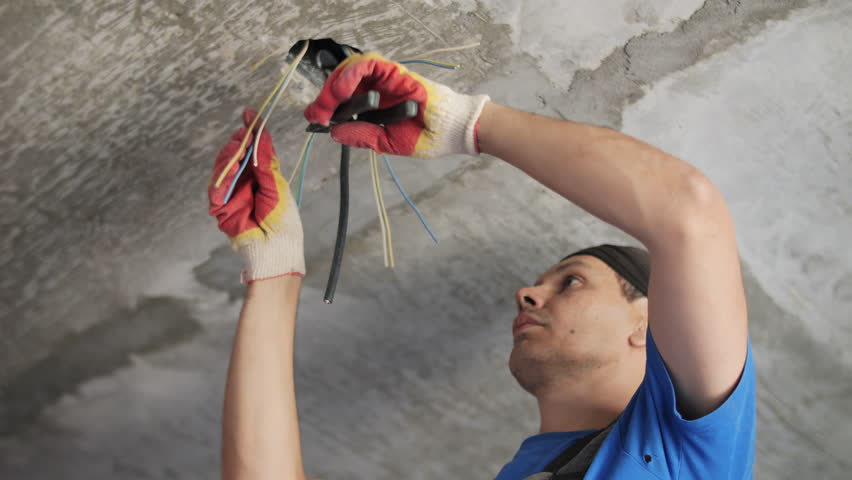 Electrician installing and connecting ceiling wiring
