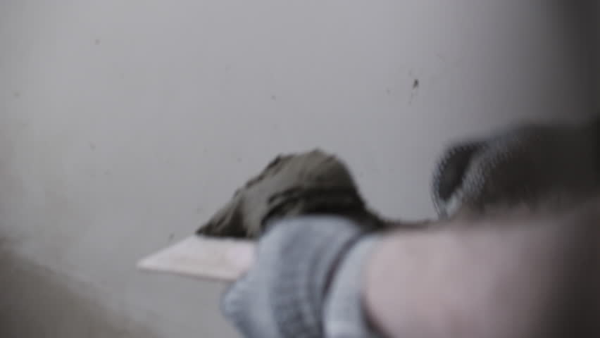 Worker holding tile adhesive on trowel before application