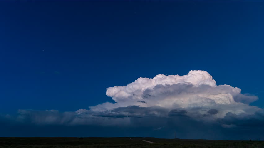 Thunderstorm clouds twist in powerful rotation beneath streaks of sunlight, showcasing dramatic structure, vivid contrasts, and the raw atmospheric energy of nature in motion