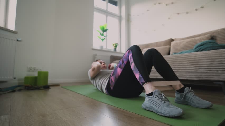 Girl Doing Fitness Exercises With Rubber Resistance Band, Doing Abs Exercises On A Floor