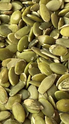 healthy green peeled pumpkin seeds are poured onto a plate healthy fats nutrition calories autumn
