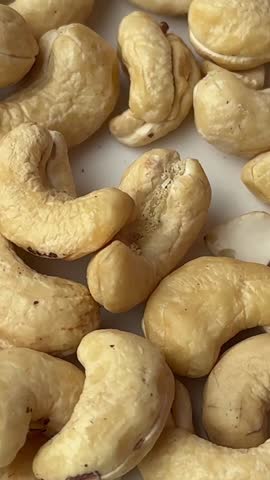 Cashew nuts standing on a white background and a female hand taking one healthy fats calories background