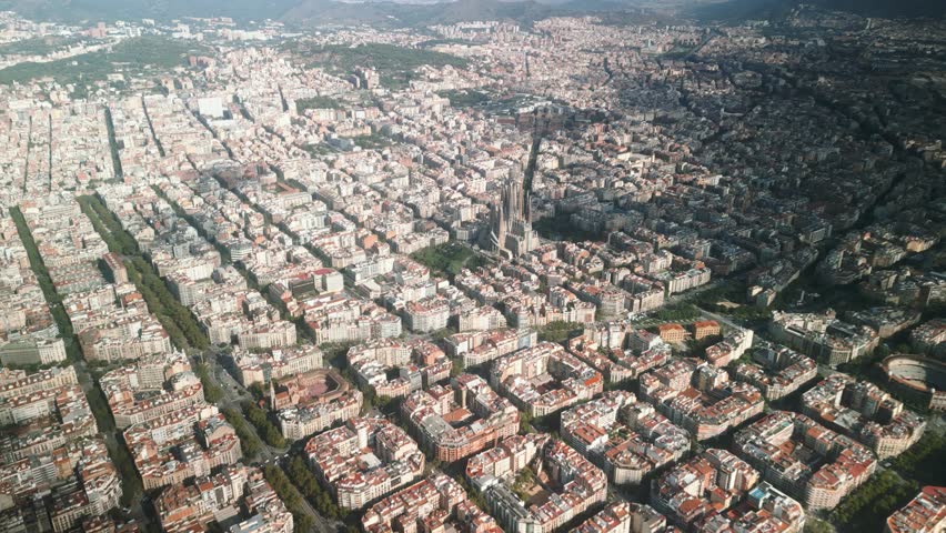4K drone aerial view of Sagrada Familia and Eixample district in Barcelona, Spain, showing iconic architecture, grid city design and Mediterranean skyline on a sunny day