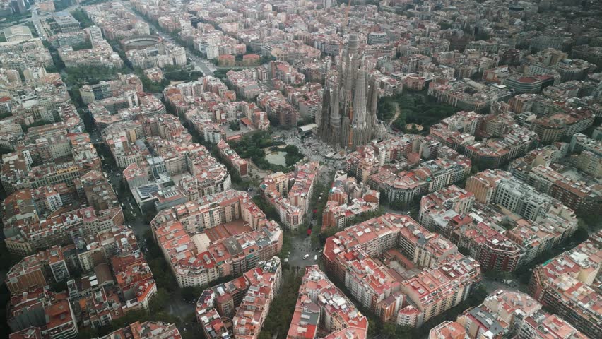 4K drone aerial view of Sagrada Familia and Eixample district in Barcelona, Spain, showing iconic architecture, grid city design and Mediterranean skyline on a sunny day