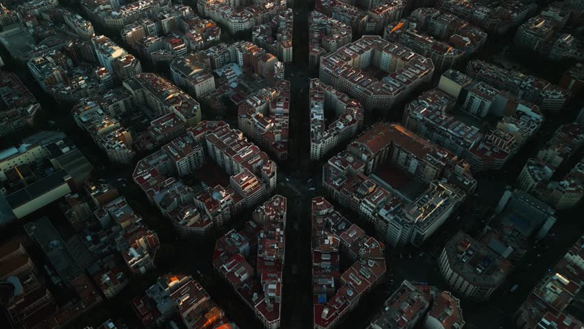 4K drone aerial view of Sagrada Familia in Barcelona at sunset, showing golden light over Eixample district and iconic grid city pattern, Catalonia, Spain