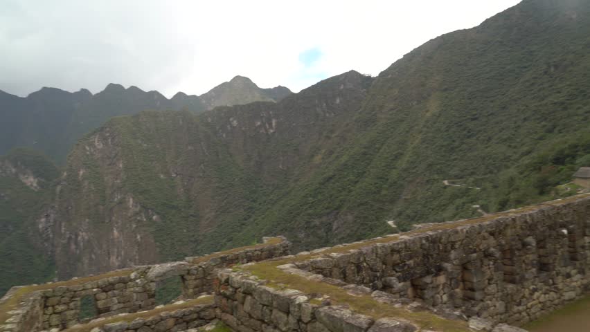 Panning shot starts on mountainside and moves to frame  empty, atmospheric interior of the Royal Palace, reveals distant terraces with tiny tourists and mountains shrouded in fog, creating a layered