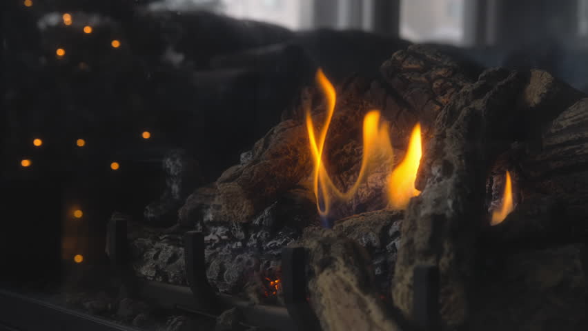 Dolly shot of a fireplace burning next to a Christmas tree at home. Slow motion.