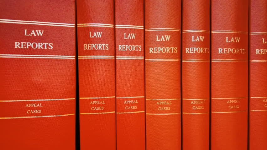 Close up of various red law books containing reports of important legal cases, stacked on a shelf with gilt titles and pristine spines
