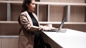 Eight months pregnant Asian woman in a suit. A pregnant businesswoman is busy typing on a laptop in an office and is a pregnant employee. - Powered by Shutterstock - Get 15% off with code: PIKWIZARD15
