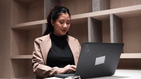 Eight months pregnant Asian woman in a suit. A pregnant businesswoman is busy typing on a laptop in an office and is a pregnant employee. - Powered by Shutterstock - Get 15% off with code: PIKWIZARD15