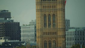 Tilt shot of ornate Gothic spires of the Victoria Tower, part of the Palace of Westminster in London, with the Union Jack flag flying atop under an overcast sky. - Powered by Shutterstock - Get 15% off with code: PIKWIZARD15