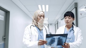 Female doctors scanning chest X-ray film walking corridor watching AR icons mapping vital signs. Medical, healthcare, technology, innovation, collaboration, diagnostics, futurism - Powered by Shutterstock - Get 15% off with code: PIKWIZARD15
