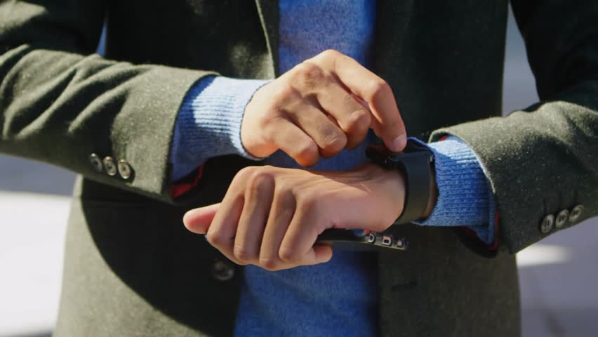 Man tapping smartwatch and activating hologram displaying social metrics on watch and smartphone. Technology, innovation, futurism, digital, mobile, connectivity, user interface - Powered by Shutterstock - Get 15% off with code: PIKWIZARD15