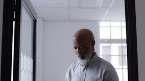 Man tapping smartphone by office window and multiplying social media metrics icons around glass. Professional, digital, minimalist, technology, communication, networking, business - Powered by Shutterstock - Get 15% off with code: PIKWIZARD15