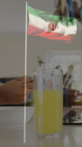 Child eating breakfast at home with Iranian flag animation overlay. Family, morning, kitchen, international, culture, tradition