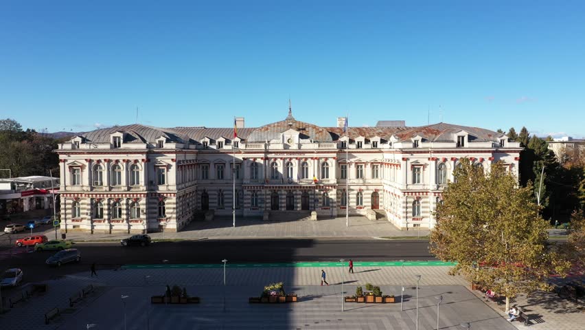 High-angle aerial shot of the majestic Palatul Administrativ in Bacau, Romania, home to the County Council. The historic architecture is bathed in bright sunlight on a clear autumn or early winter day