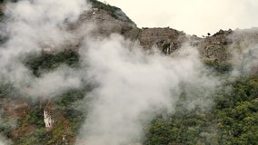 A cinematic drone shot starts with a close-up of the misty side of the Machu Picchu citadel and its terraces, then rises vertically to reveal a stunning top-down view of the entire ancient structure - Powered by Shutterstock - Get 15% off with code: PIKWIZARD15
