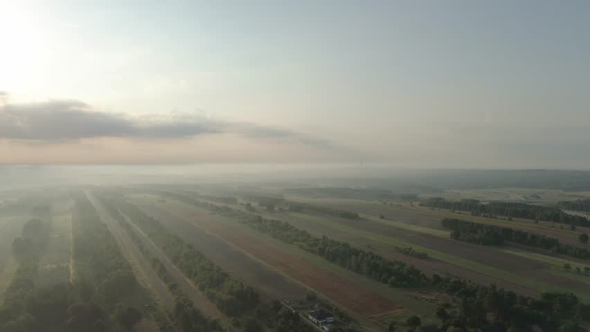 Soft sunlight through fog over village landscape