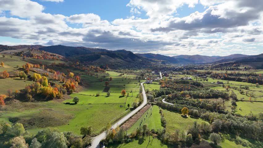 Car driving on winding road in autumn colors in Bucovina Romania