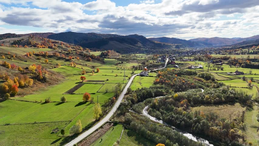 Drone footage near Mănăstirea Humorului showing road, river, and colorful autumn countryside in Bucovina, Romania