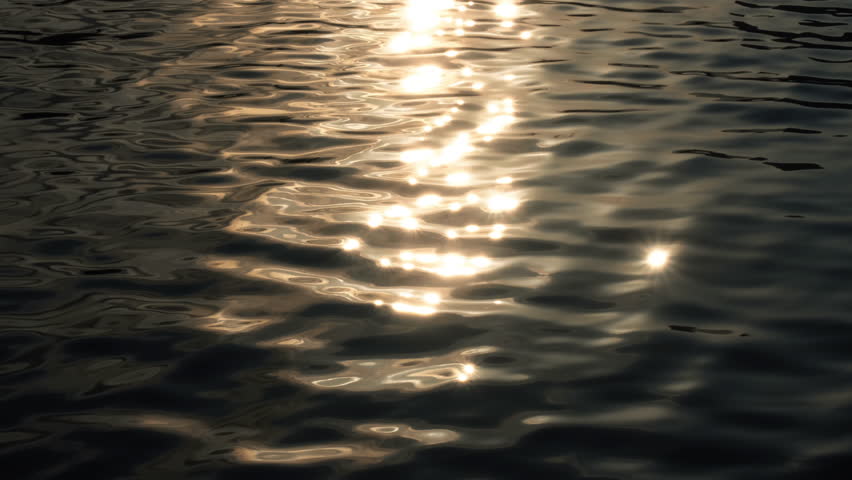 Slow motion of golden glittering sea surface, abstract background.