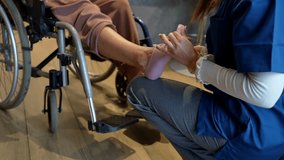 Professional physical therapist helping a disabled patient in a wheelchair by massaging and stretching their injured foot and ankle during a rehabilitation session in a clinic or at home - Powered by Shutterstock - Get 15% off with code: PIKWIZARD15