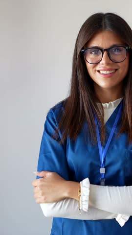Portrait of a confident young nurse and a senior female doctor standing together with crossed arms, looking at the camera and smiling, isolated on a white background in a hospital setting