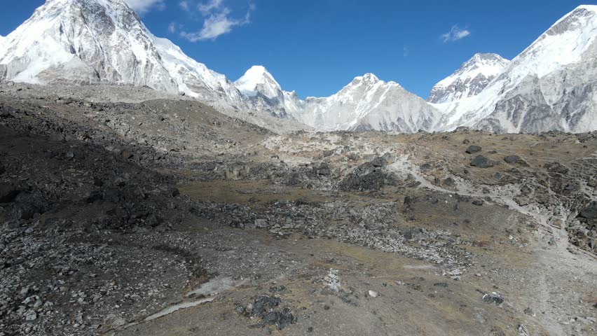 Drone footage of Everest Base Camp in Solukhumbu District, Nepal, showing rugged rocky landscape, glaciers, and majestic Himalayan peaks under a clear blue sky.