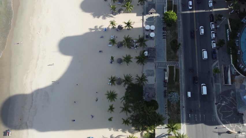4K drone aerial of Da Nang's vibrant coastline. Modern high-rise hotels cast long shadows over the golden sand of My Khe Beach and the South China Sea in Vietnam, showcasing a popular resort city.
