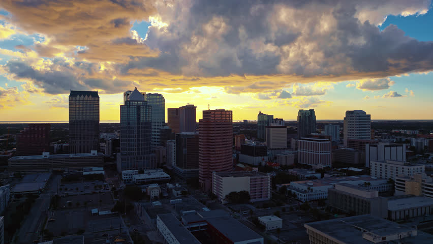 Tampa skyline at dusk dramatic clouds glowing in the sky from the warm setting sun and the warm light reflects on the tall buildings.