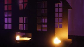 A solitary candle burns softly, casting flickering shadows through the windows of a castle. The dim light creates an atmosphere of fear and mystery on Halloween night. Purple, orange and black colors - Powered by Shutterstock - Get 15% off with code: PIKWIZARD15